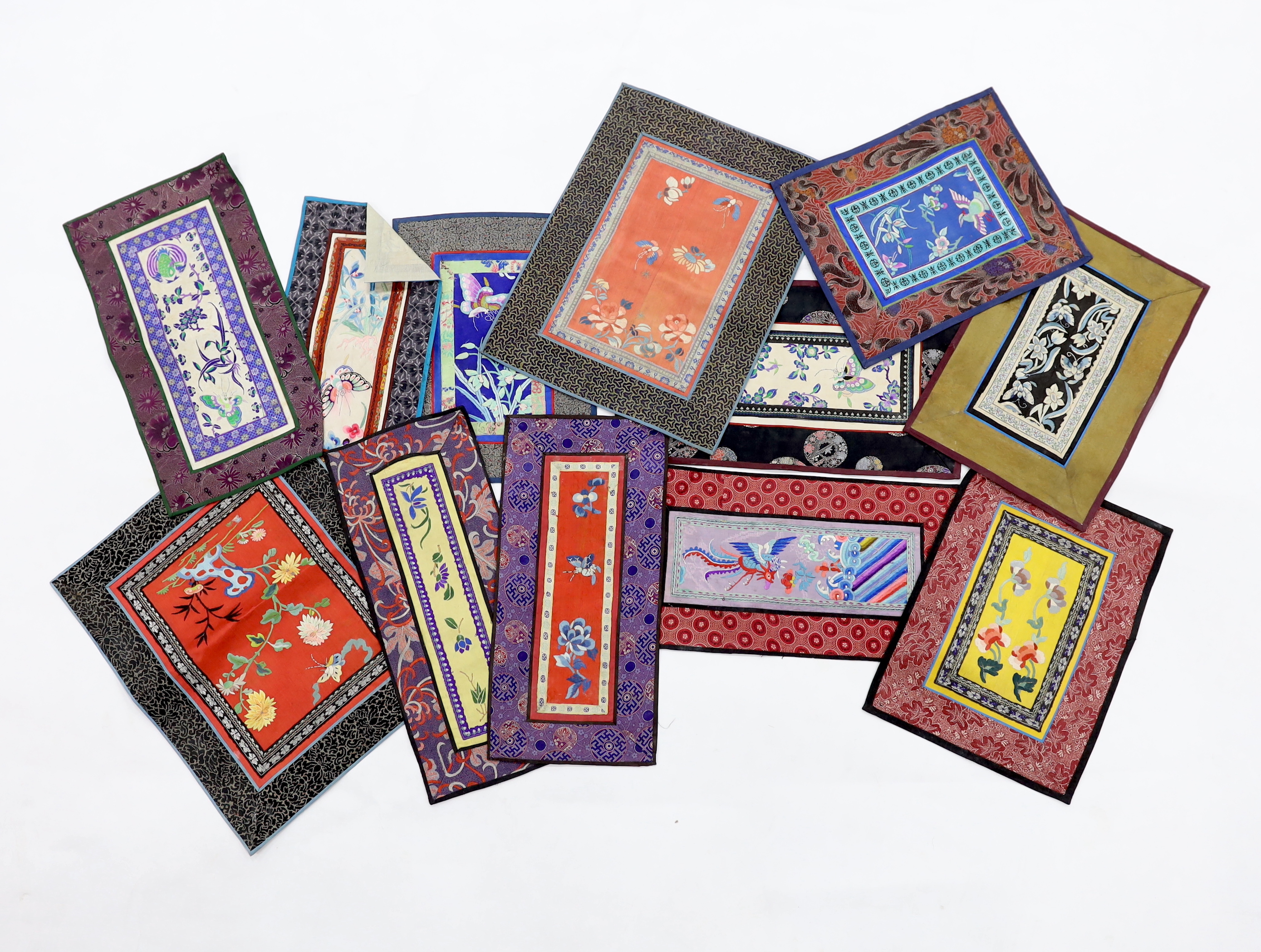 Twelve various Chinese rectangular silk polychrome embroidered mats with damask borders, of varying sizes